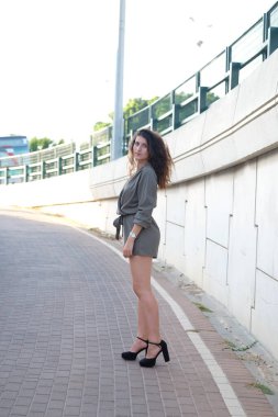 Güzel esmer kadın şehrin sokaklarında poz veriyor.