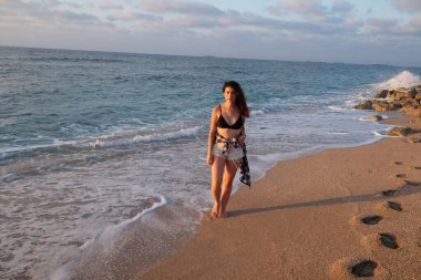 Kumsalda sırt çantalı güzel genç bir kadın.