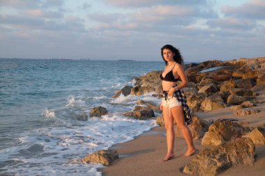 Gün batımında kumsalda güzel bir kadın.