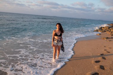 Sahilde gün batımında genç ve güzel bir kadın.