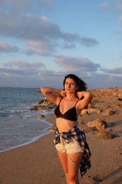 Okyanusun arka planında mavi bikinili bir kız ve gün batımı