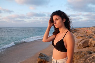 Sahilde gün batımında genç bir kadın