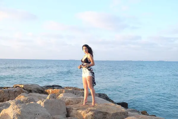 Kumsalda sırt çantalı genç bir kadın.