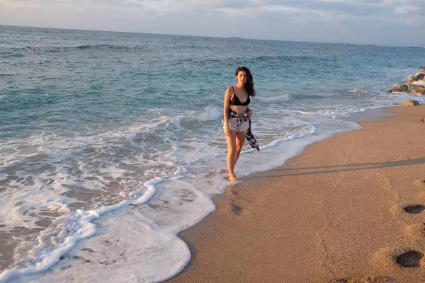 Güzel bir kız akşam deniz kıyısında yürüyor.