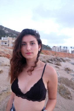 Kumsalda siyah mayosu olan güzel, genç bir esmer.