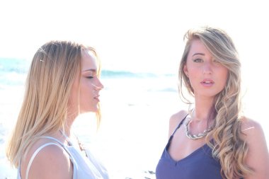 Gün batımında tropik bir plajda poz veren iki genç bayan en iyi arkadaş.