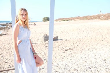 Uzun sarı saçlı, beyaz elbiseli bir kız.