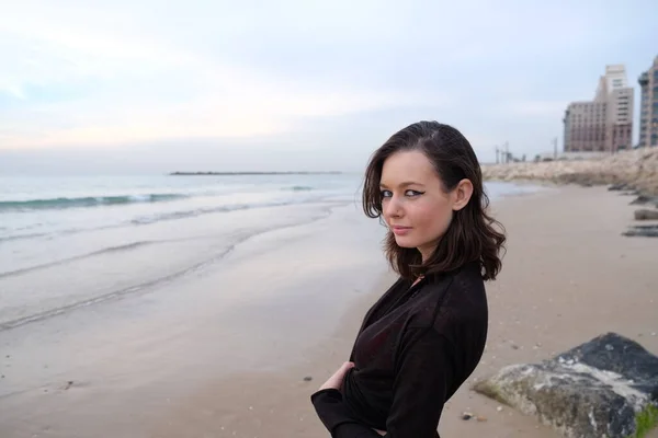 beautiful woman with black hair and dark brown eyes posing at sea beach