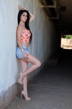 Genç bir kadın yazın şehir parkında poz veriyor.