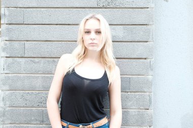 Sarışın, güzel bir kadın. Uzun saçlı, uzun gözlü. Eski binanın önünde poz veriyor..