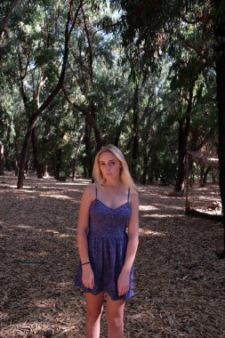 Ormanın ortasındaki parkta poz veren güzel sarışın bir manken.