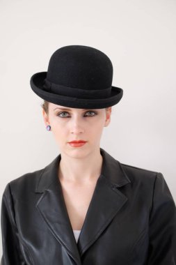 Siyah şapkalı ve beyaz ceketli güzel bir genç kadın. Siyah elbiseli ve şapkalı bir kızın moda fotoğrafı..