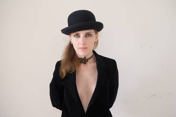 beautiful girl in black hat and black suit posing on white background