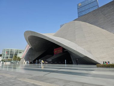 Shenzhen, Çin - 17 Ocak 2025: MOCAPE 'in ikonik' Bulut 'heykeli modern müze alanını keşfeden ziyaretçilerle birlikte geniş geometrik tavan penceresini yansıtıyor.