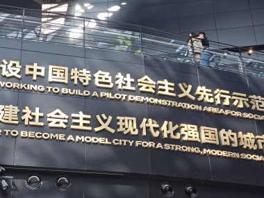 Shenzhen, Çin - 17 Ocak 2025: MOCAPE 'in ikonik' Bulut 'heykeli modern müze alanını keşfeden ziyaretçilerle birlikte geniş geometrik tavan penceresini yansıtıyor.