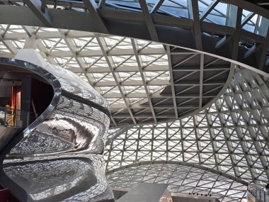 Shenzhen, Çin - 17 Ocak 2025: MOCAPE 'in ikonik' Bulut 'heykeli modern müze alanını keşfeden ziyaretçilerle birlikte geniş geometrik tavan penceresini yansıtıyor.