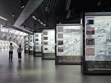 Shenzhen, Çin - 17 Ocak 2025: MOCAPE 'in ikonik' Bulut 'heykeli modern müze alanını keşfeden ziyaretçilerle birlikte geniş geometrik tavan penceresini yansıtıyor.