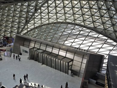 Shenzhen, Çin - 17 Ocak 2025: MOCAPE 'in ikonik' Bulut 'heykeli modern müze alanını keşfeden ziyaretçilerle birlikte geniş geometrik tavan penceresini yansıtıyor.