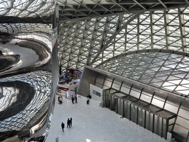 Shenzhen, Çin - 17 Ocak 2025: MOCAPE 'in ikonik' Bulut 'heykeli modern müze alanını keşfeden ziyaretçilerle birlikte geniş geometrik tavan penceresini yansıtıyor.