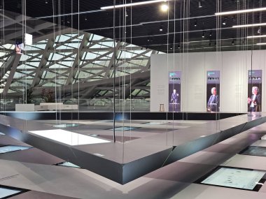 Shenzhen, Çin - 17 Ocak 2025: MOCAPE 'in ikonik' Bulut 'heykeli modern müze alanını keşfeden ziyaretçilerle birlikte geniş geometrik tavan penceresini yansıtıyor.