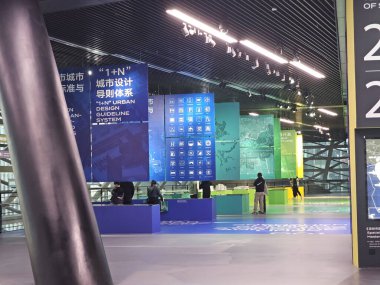 Shenzhen, Çin - 17 Ocak 2025: MOCAPE 'in ikonik' Bulut 'heykeli modern müze alanını keşfeden ziyaretçilerle birlikte geniş geometrik tavan penceresini yansıtıyor.