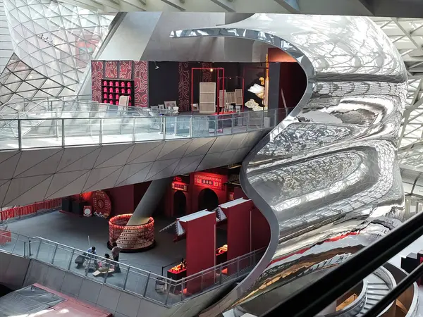 Shenzhen, Çin - 17 Ocak 2025: MOCAPE 'in ikonik' Bulut 'heykeli modern müze alanını keşfeden ziyaretçilerle birlikte geniş geometrik tavan penceresini yansıtıyor.