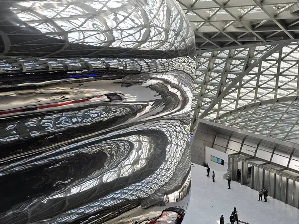 Shenzhen, Çin - 17 Ocak 2025: MOCAPE 'in ikonik' Bulut 'heykeli modern müze alanını keşfeden ziyaretçilerle birlikte geniş geometrik tavan penceresini yansıtıyor.