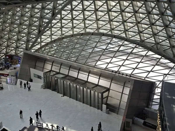 Shenzhen, Çin - 17 Ocak 2025: MOCAPE 'in ikonik' Bulut 'heykeli modern müze alanını keşfeden ziyaretçilerle birlikte geniş geometrik tavan penceresini yansıtıyor.