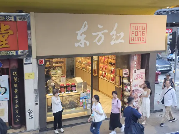 Hong Kong, Çin - 6 Haziran 2025: Tung Fong Hung mağazası girişi, kalabalık şehir caddesinde yayaların yürüdüğü geleneksel bir Çin sağlık ürünleri ve tonik dükkanı.