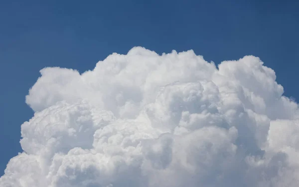 Mavi gökyüzündeki pamuk gibi büyük, beyaz ve tüylü bir bulutun fotoğrafı..