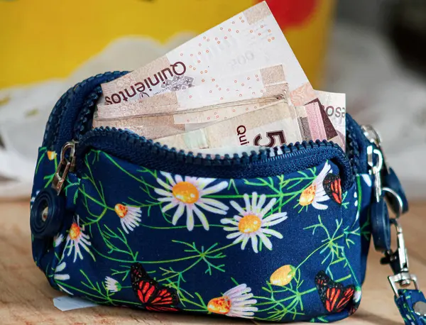 Photo of a colorful purse full of a 5 Hundred bills Mexican pesos