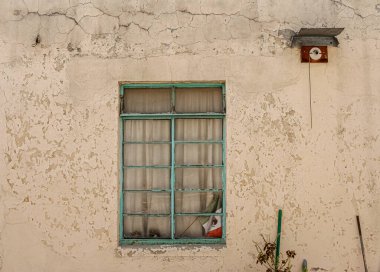 Photo of a window painted in a aqua color, of a derelict house, plants and a Mexican flag was forgotten. clipart