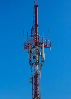 Mavi gökyüzü arka planına sahip kırmızı ve beyaz telekomünikasyon direği