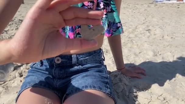 彼女は手で砂から小さな心臓をこすっている 高品質の4K映像 — ストック動画