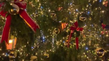 Kırmızı kurdeleler ve ışıklarla parıldayan Noel ağacı. Yüksek kalite 4k görüntü