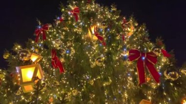 Kırmızı kurdeleler ve ışıklarla parıldayan Noel ağacı. Yüksek kalite 4k görüntü