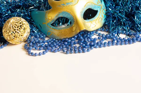 Beads and tinsel for new year mask on light background. New Year decoration with a mask
