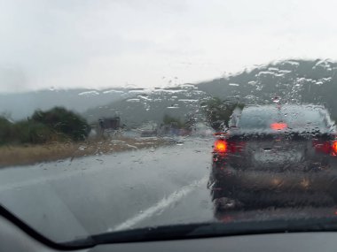 Yoldaki araba ıslak bir pencereden geçiyor.