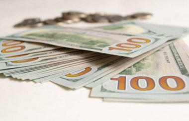 100 dolarlık banknotlar yakın plan, arkasında bozuk paralar var.