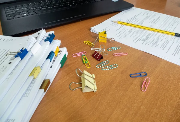 There are paper clips and a document and a pencil on the table