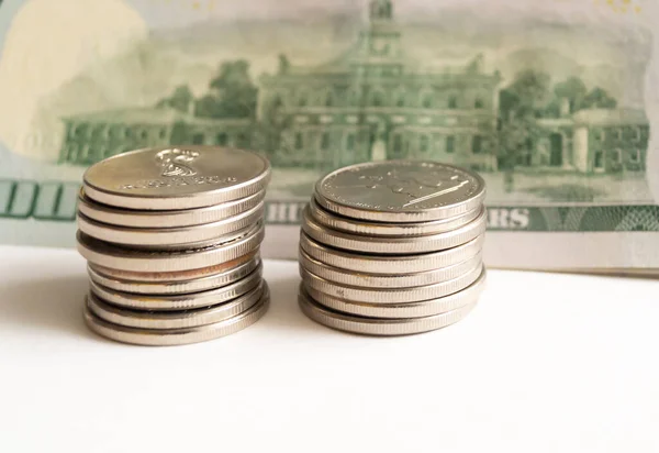 100 dolarlık banknotun arka planında bir yığın bozuk para var..