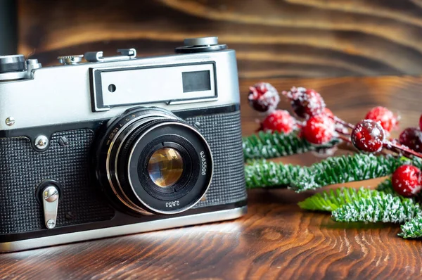 Vintage film camera and film, Christmas tree branch with ornaments on wooden background