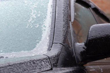 Buzlu araba aynası, cam ve yan kapılar. Dondurucu yağmurdan sonra kış günü buzlu bir araba.