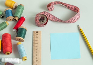 Dikiş dikmek için arka plan. Hafif bir arka planda dikiş malzemeleri. İplik, makas, düğme, mezura, dikiş aksesuarları. dizüstü bilgisayar