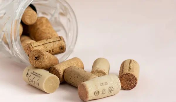 wine corks scattered from a glass mug on a light-colored background