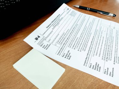 Ofis masasında kalem defteri olan W-4 vergi formunun görüntüsü. Evrak işleri, vergilendirme kavramı