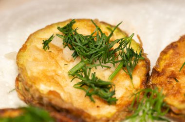 Kızarmış kabak dilimleri üzerine doğranmış maydanoz serpilmiş.