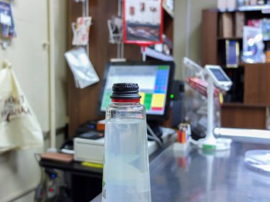 Markette şarap seçen bir kadın, çeşitli içkilerle sergilenen bir vitrin, alışveriş için kasada kart ile ödeme yapan bir kadın.