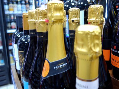 Markette şarap seçen bir kadın, çeşitli içkilerle sergilenen bir vitrin