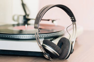 Kulaklıklar ve vinil pikabın yakın çekimi vinil plaktaki kartuşun yakın çekimi, analog retro müzik, vinil disk koleksiyonu, antika ekipmanlar.